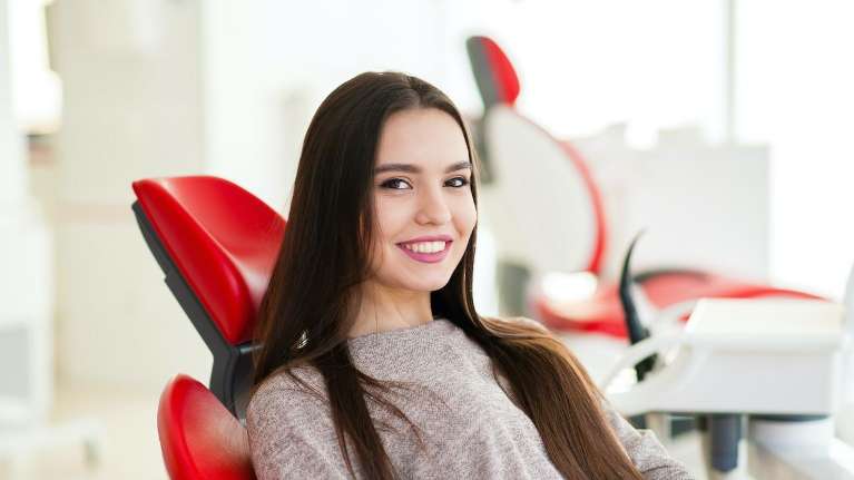 woman sitting in a red dental chair