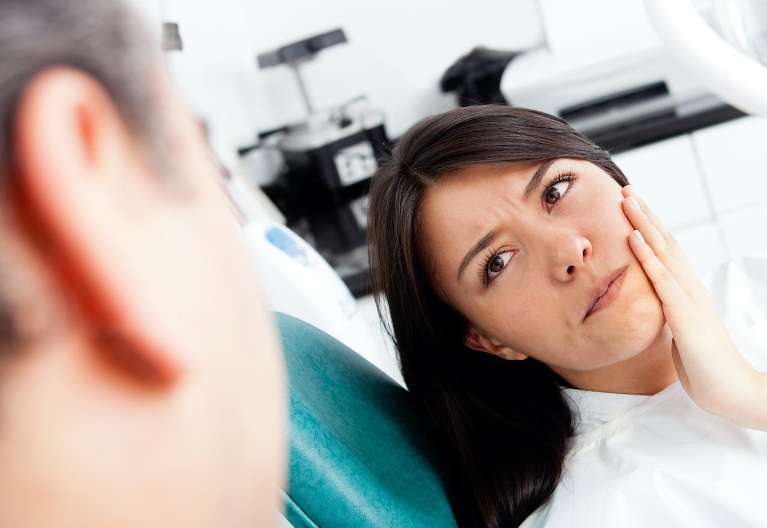woman in dental pain holding her left cheek